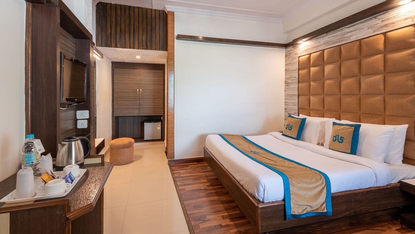 A welcoming hotel room with a comfortable bed, a TV, a mini-fridge, and a balcony offering a view - DLS Meghavan Resort